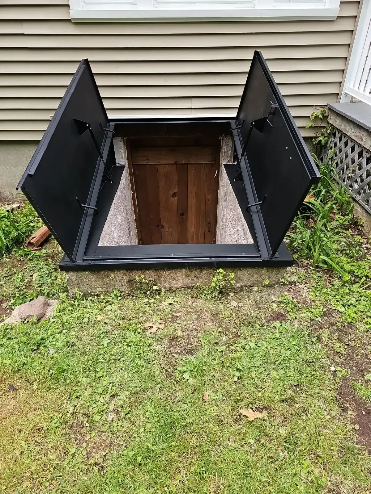 A finished basement entry with concrete stairs and a welded steel hatchway